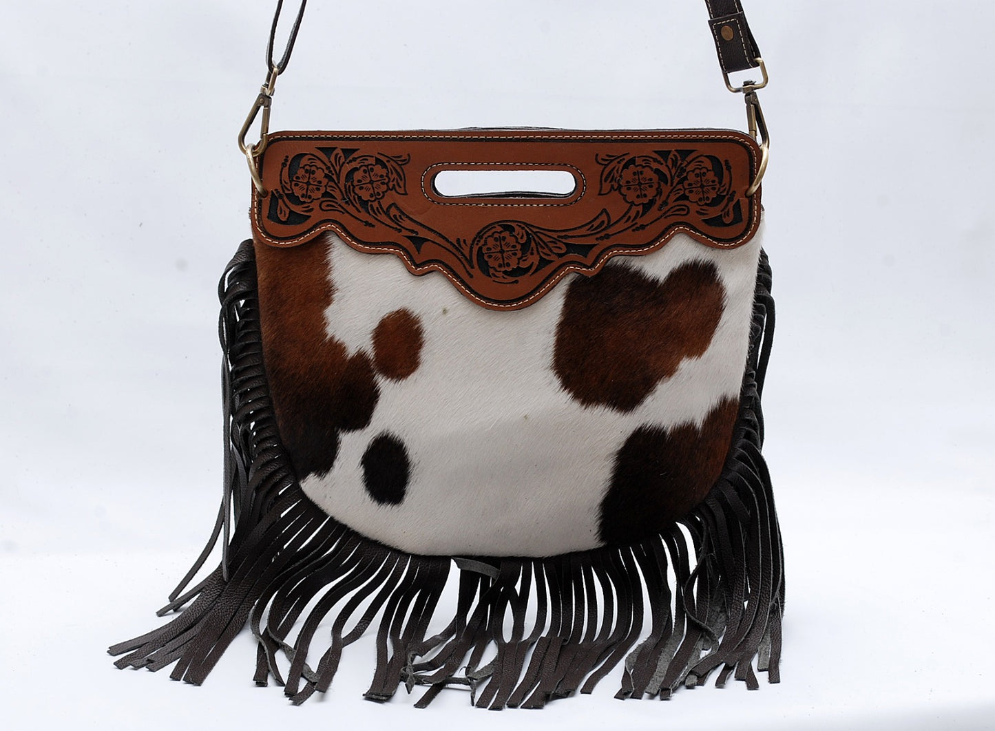 Cowhide leather handbag with brown and white pattern and black fringe on a white background