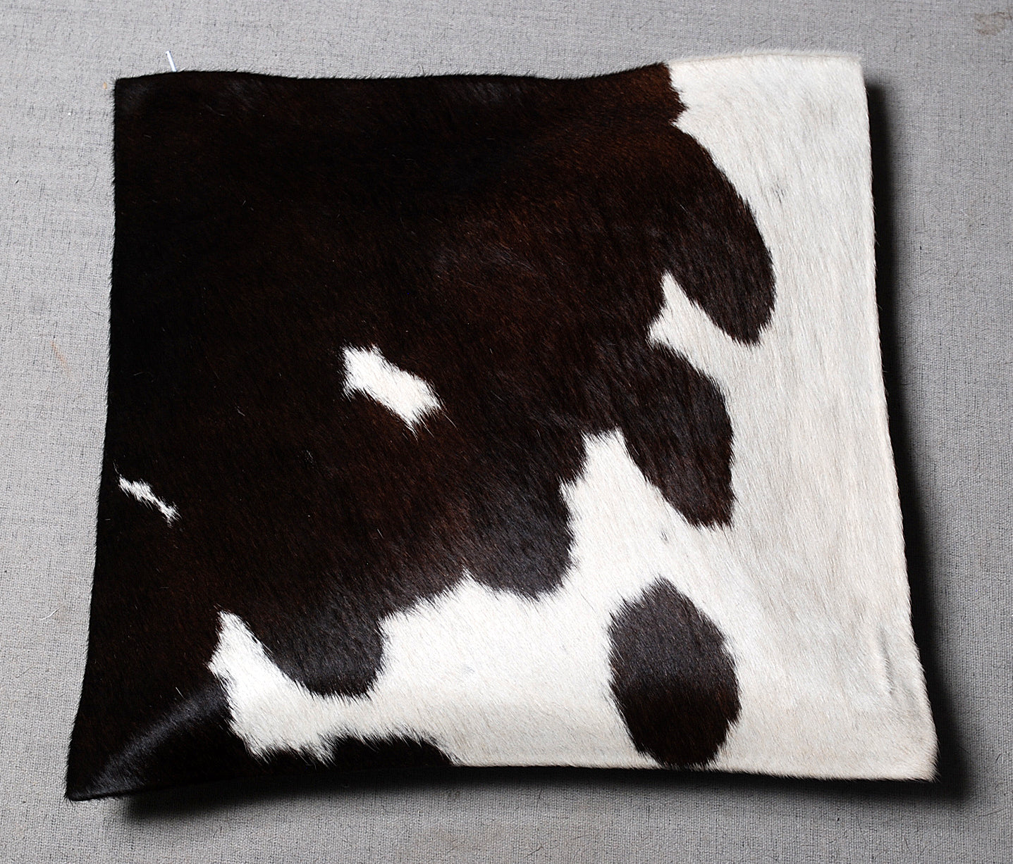 Cow print pillow on a gray background
