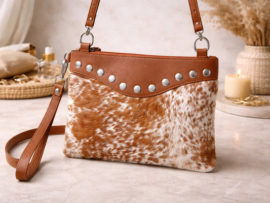 Brown and white cowhide handbag with studded details.