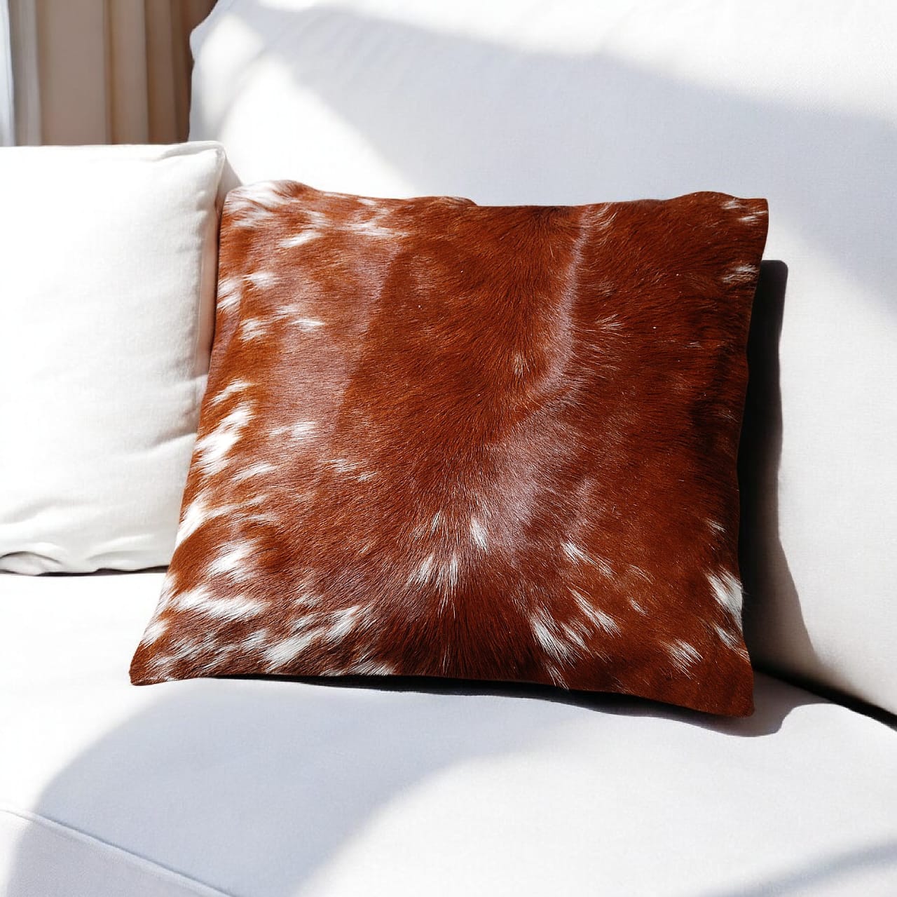 Brown and white cowhide pillow on a white sofa