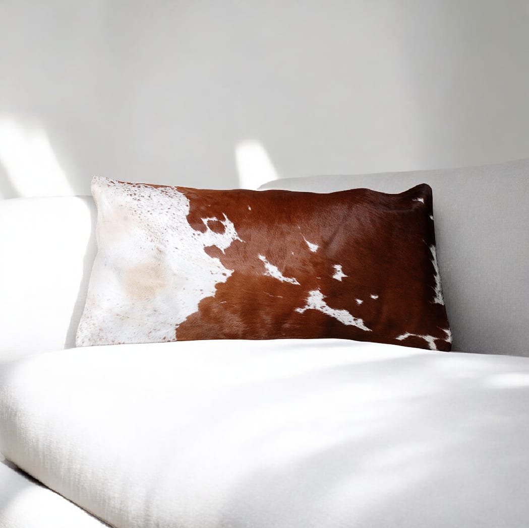 Brown and white cowhide pillow on a white bed