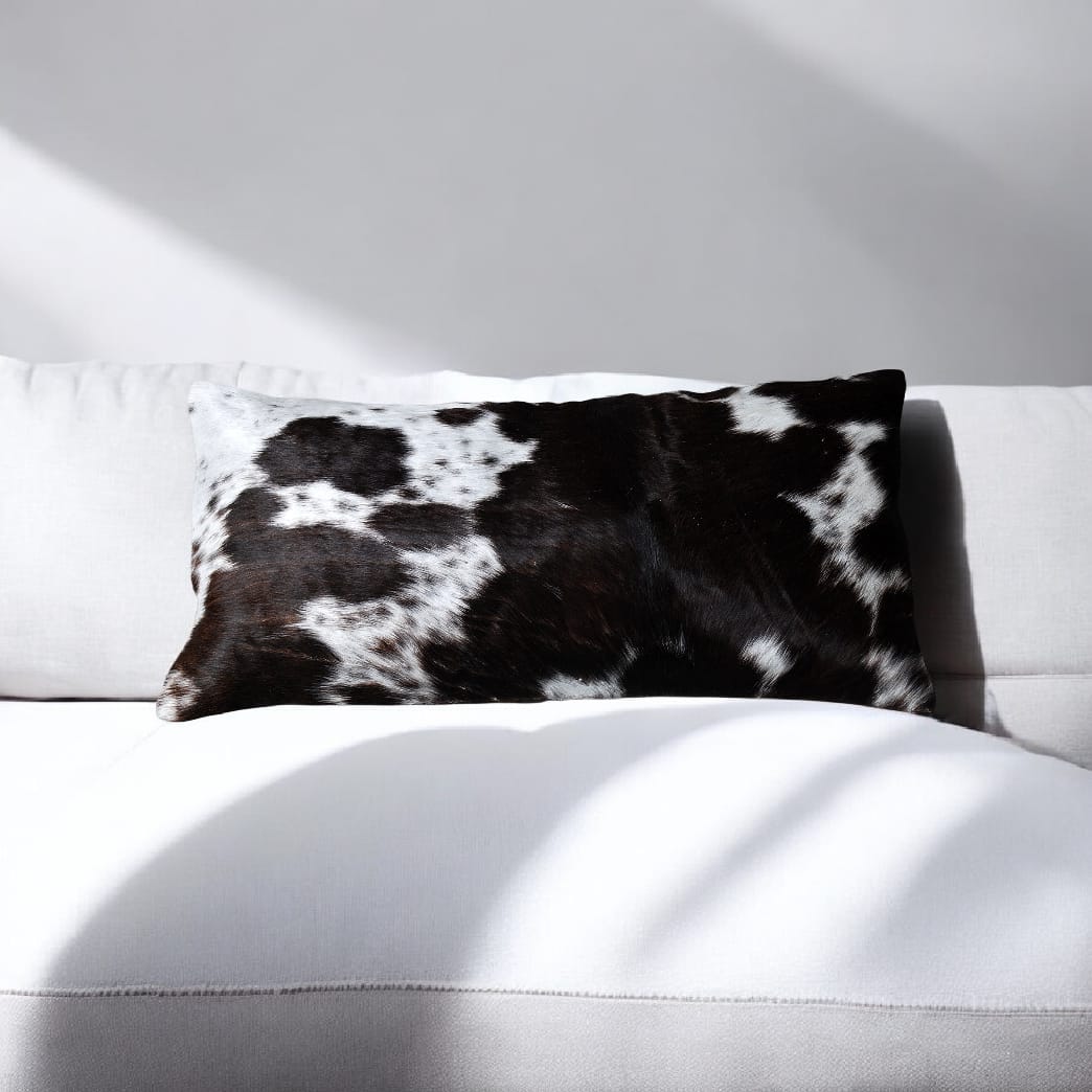Black and white cowhide pillow on a white sofa